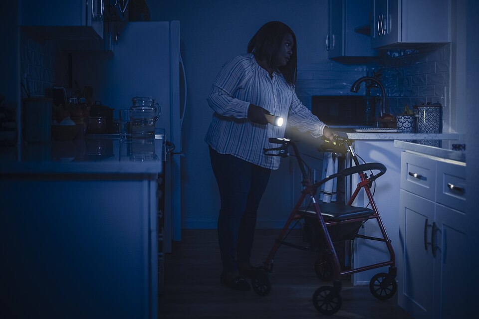 Storm_Safety_-_Person_who_uses_a_walker_using_a_flashlight_in_their_kitchen_during_a_power_outage